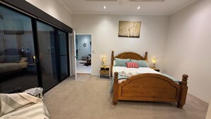 A bedroom with a large sliding glass door leading to a balcony, a wooden bed with pillows, a bedside table with a lamp, and a wall-mounted artwork. - Waterlink Retreat - canal views with easy access to both the canal and the river (South Yunderup)