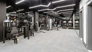 Een moderne sportschool met diverse fitnessapparaten, waaronder loopbanden en gewichtstoestellen, en een ruime indeling.