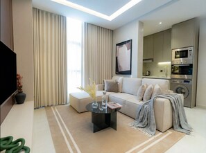 A modern living room with a sofa, coffee table, and a flat-screen TV. - LIV by Yamama - Al Nada (Riyadh)