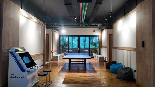 Une chambre dotée d’une table de ping-pong, d’un mini-bar et offrant une vue sur les arbres grâce à de grandes fenêtres.
