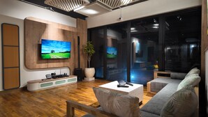 A modern living room with a flat-screen TV mounted on a wooden wall, a coffee table, and a sofa.