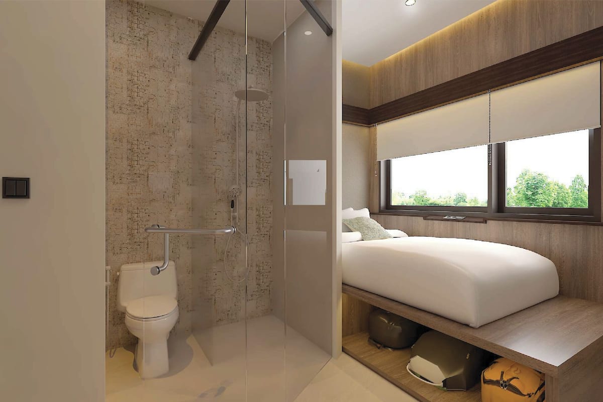 Un baño moderno con cabina de ducha de vidrio, inodoro y cama con ventana superior.