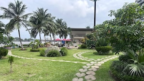 A garden pathway with heart-shaped stepping stones, palm trees, and a trash can. - Sublime T2 Le Plateau Lagoon view Bright Large Ventilated (Abidjan)