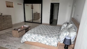 A bedroom with a bed, bedside table, lamp, and a dresser. - Sublime T2 Le Plateau Lagoon view Bright Large Ventilated (Abidjan)