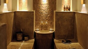 A spa room with a stone wall, a sink, and shelves with bottles. - l'ecrin marrakech (Marrakech)