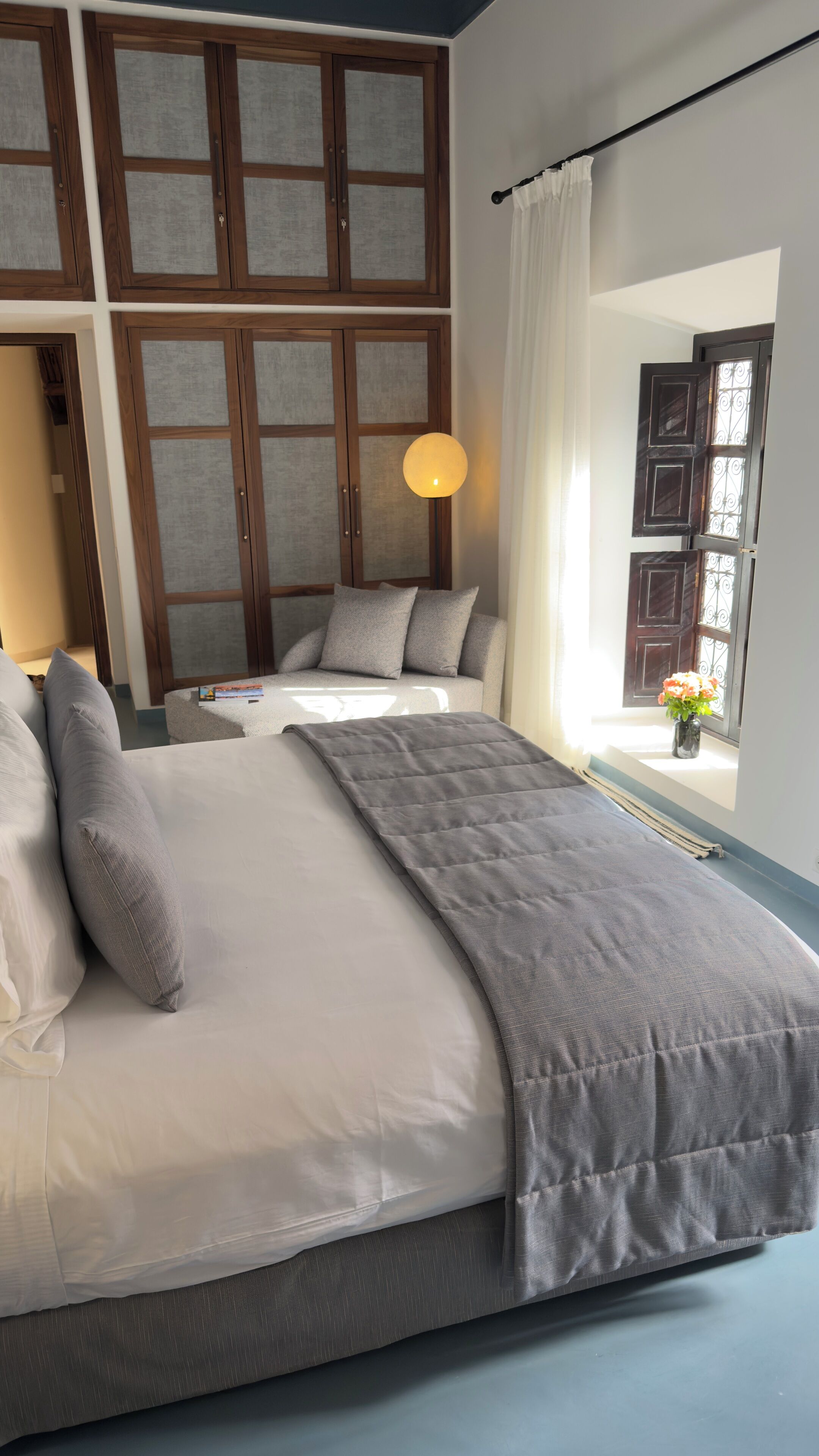 A bedroom with a large bed, a sofa, and a window with curtains.