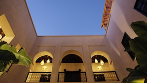 A courtyard with arched windows and a wooden ladder. - l'ecrin marrakech (Marrakech)