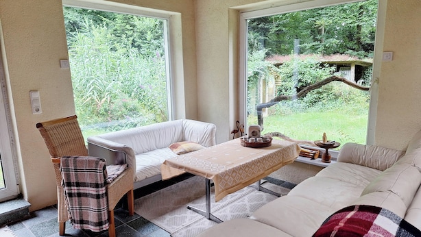 A cozy room with a white sofa, a wicker chair, and a small table with a placemat.