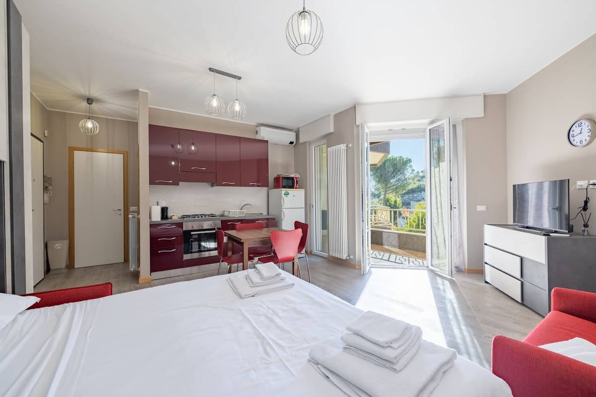 Een moderne slaapkamer met een groot bed, een eethoek, een keuken en een balkon met uitzicht.