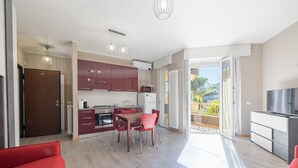 A modern kitchen with red cabinets, a dining area with a table and chairs, and a balcony with a view. - Sun & Sea Homes by Wonderful Italy (Sanremo)