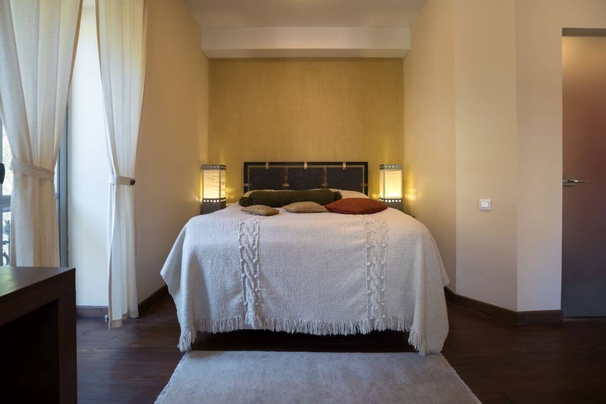 Ein Schlafzimmer mit einem Bett, Nachttischlampen, einem Beistelltisch und einer Tür.