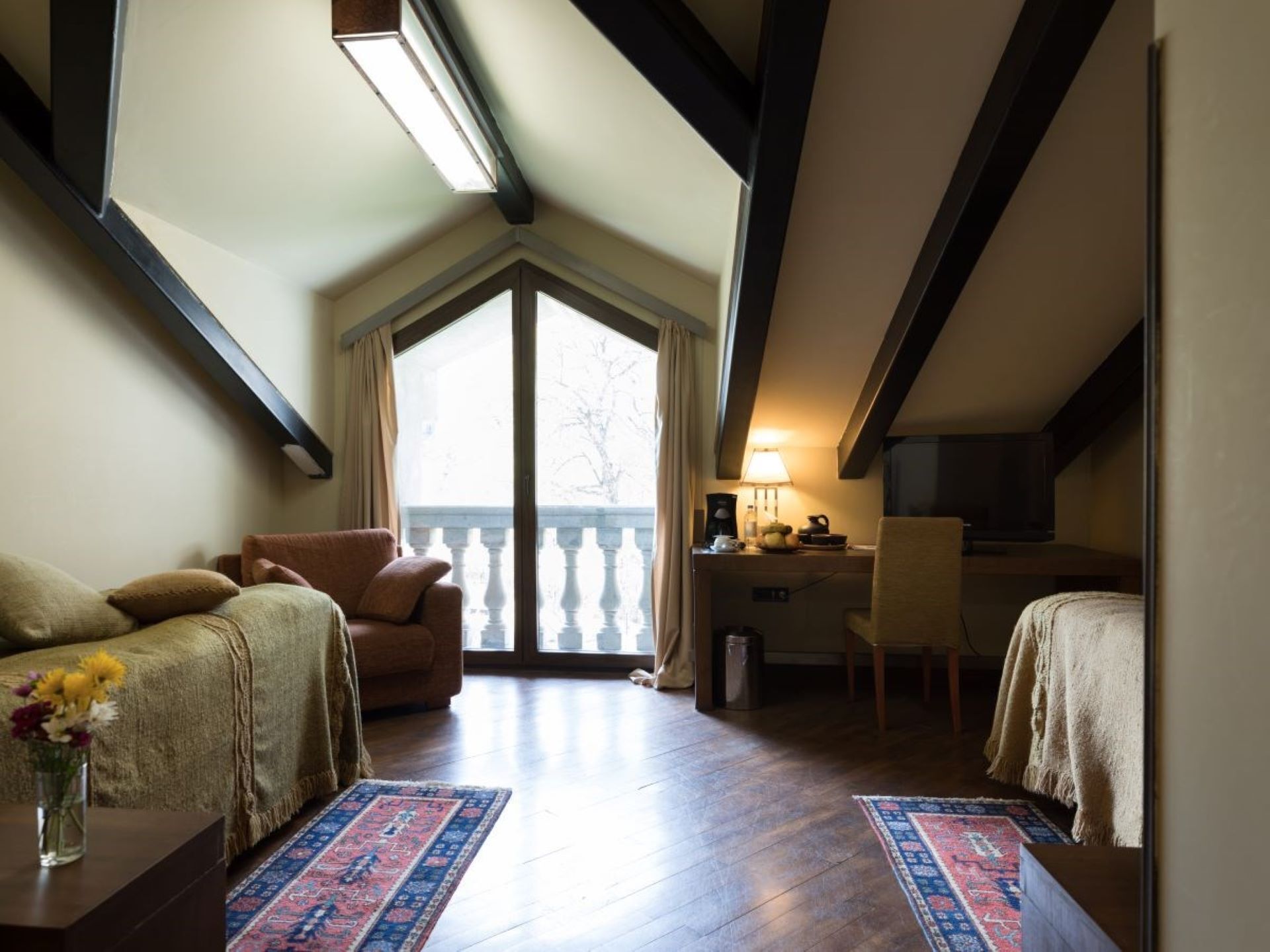 A cozy room with a large window, a desk, a chair, and a sofa.