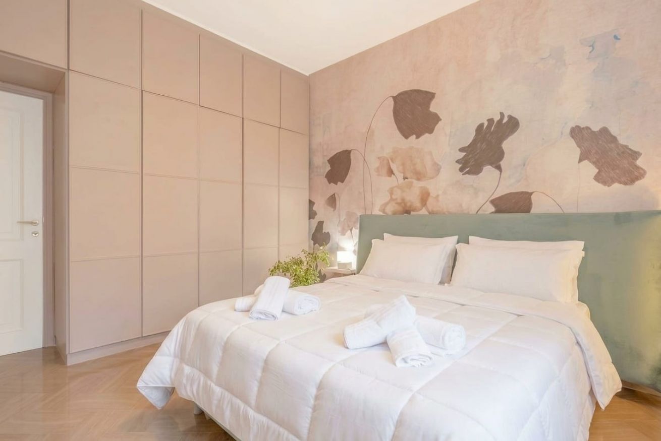 Une chambre d’hôtel avec un grand lit, une armoire et un mur orné d’un motif floral.