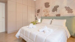 Een hotelkamer met een groot bed, een kledingkast en een muur met een bloemenprint.