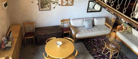 A cozy living room with a sofa, a round wooden table, and a patterned rug.