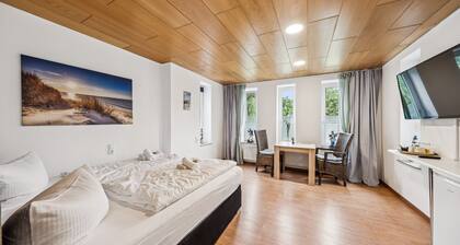 Cozy double room, seating area, flat-screen TV, and modern bathroom with shower. Ideal for couples and short stays – enjoy a relaxed atmosphere with warm wood accents and coastal charm.
