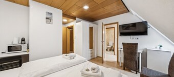 Comfortable room with a double and single bed, private bathroom, flat-screen TV, fridge, microwave, coffee machine, and cozy seating area. Ideal for small families or friends traveling together.