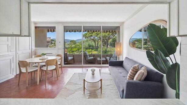 A spacious living area with a sofa, coffee table, and dining set. A large window offers a view of greenery and a distant landscape. - Apt 2BR/4P-Balcony Saint-Tropez (Saint-Tropez)