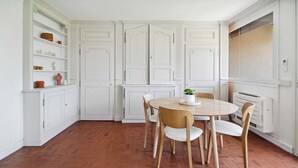 A kitchen with white cabinetry, a herringbone floor, and a round wooden table with chairs. - Apt 2BR/4P-Balcony Saint-Tropez (Saint-Tropez)