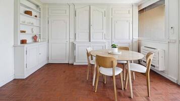A kitchen with white cabinetry, a herringbone floor, and a round wooden table with chairs.