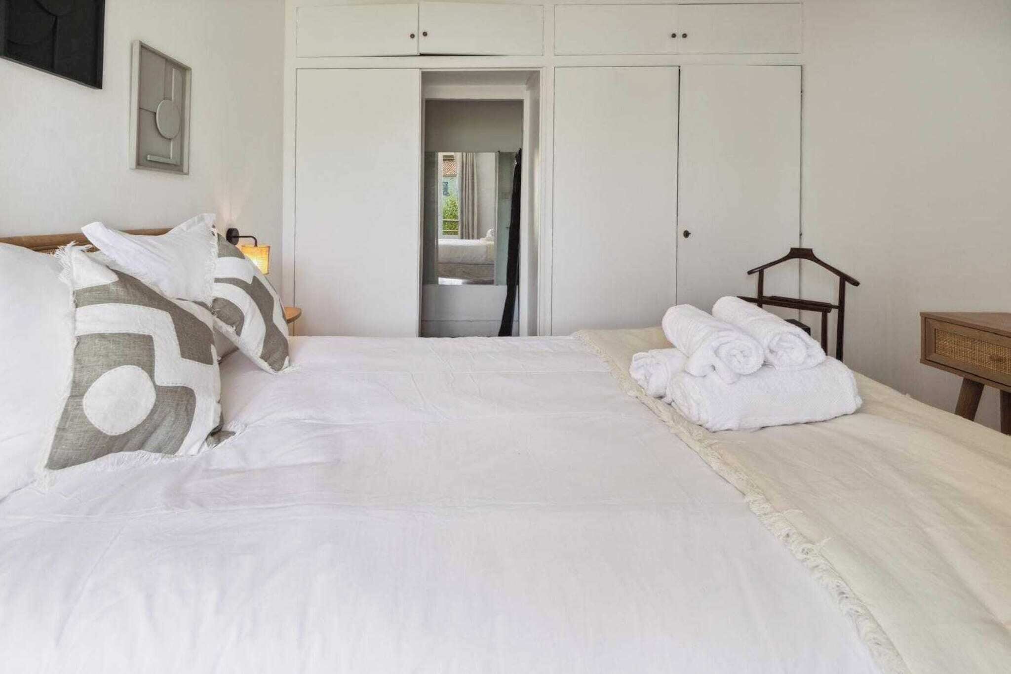 A bedroom with a large bed, a wardrobe, and a hanging rack.