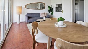 A dining area with a wooden table, chairs, a sofa, a lamp, and a potted plant. - Apt 2BR/4P-Balcony Saint-Tropez (Saint-Tropez)