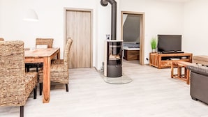Ein modernes Wohnzimmer mit Kamin, einem Essbereich mit Korbmöbeln und einem Fernseher auf einem Holzboden.