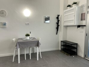 Uma sala de jantar com mesa, cadeiras, planta em vaso, relógio de parede, espelho e armário.