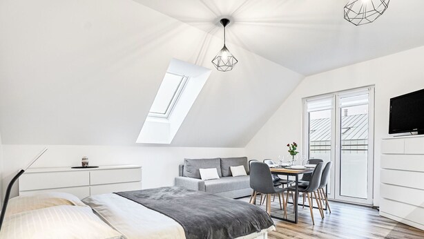 A modern bedroom with a skylight, a dining area, and a TV.