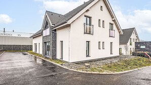 A modern two-story house with a sloped roof, stone accents, and a paved driveway.