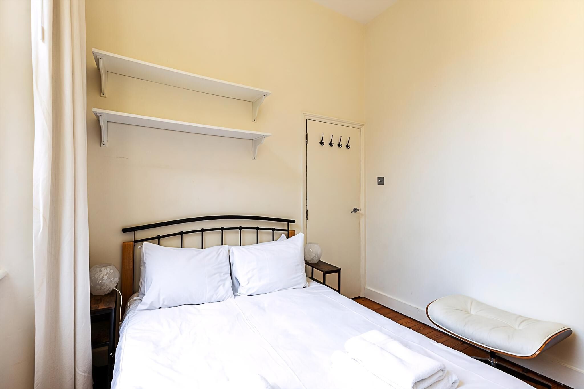 Ein Schlafzimmer mit einem Bett, einem Nachttisch, einem Schminktisch, einem Sessel und einem Kleiderschrank.