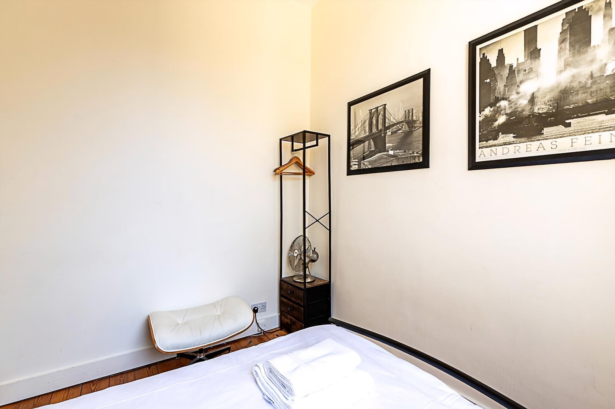 Ein Hotelzimmer mit einem Bett, einem Hängesessel, einer hohen Stehlampe und zwei gerahmten Bildern an der Wand.