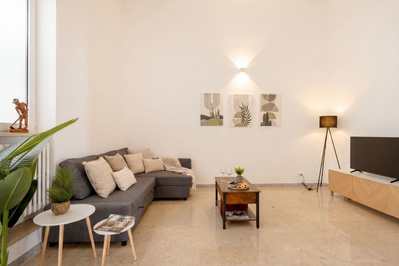 A modern living room with a grey sofa, a small round table, a floor lamp, and abstract wall art.
