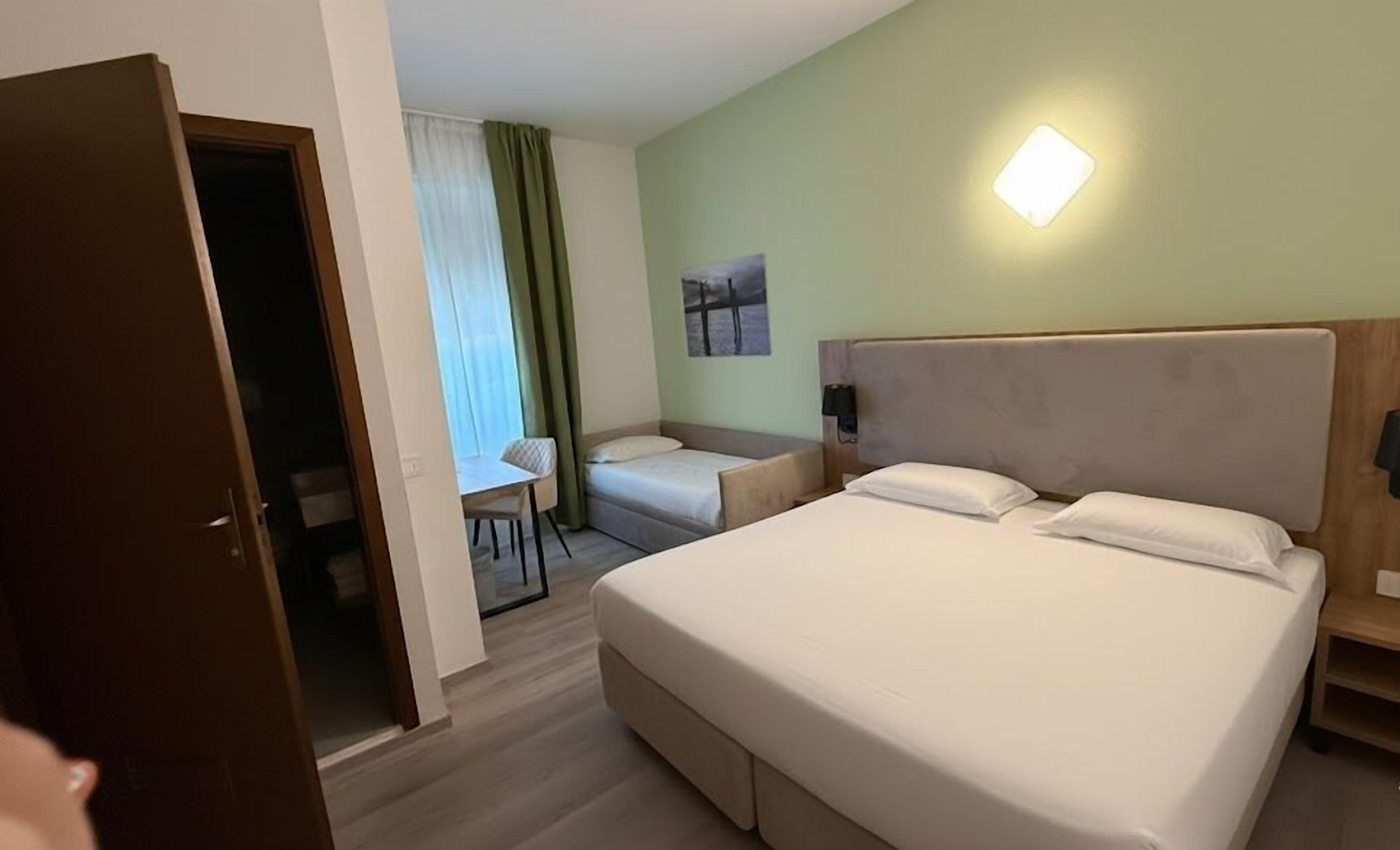 A hotel room with a large bed, a desk, and a chair.