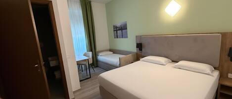 A hotel room with a large bed, a desk, and a chair.