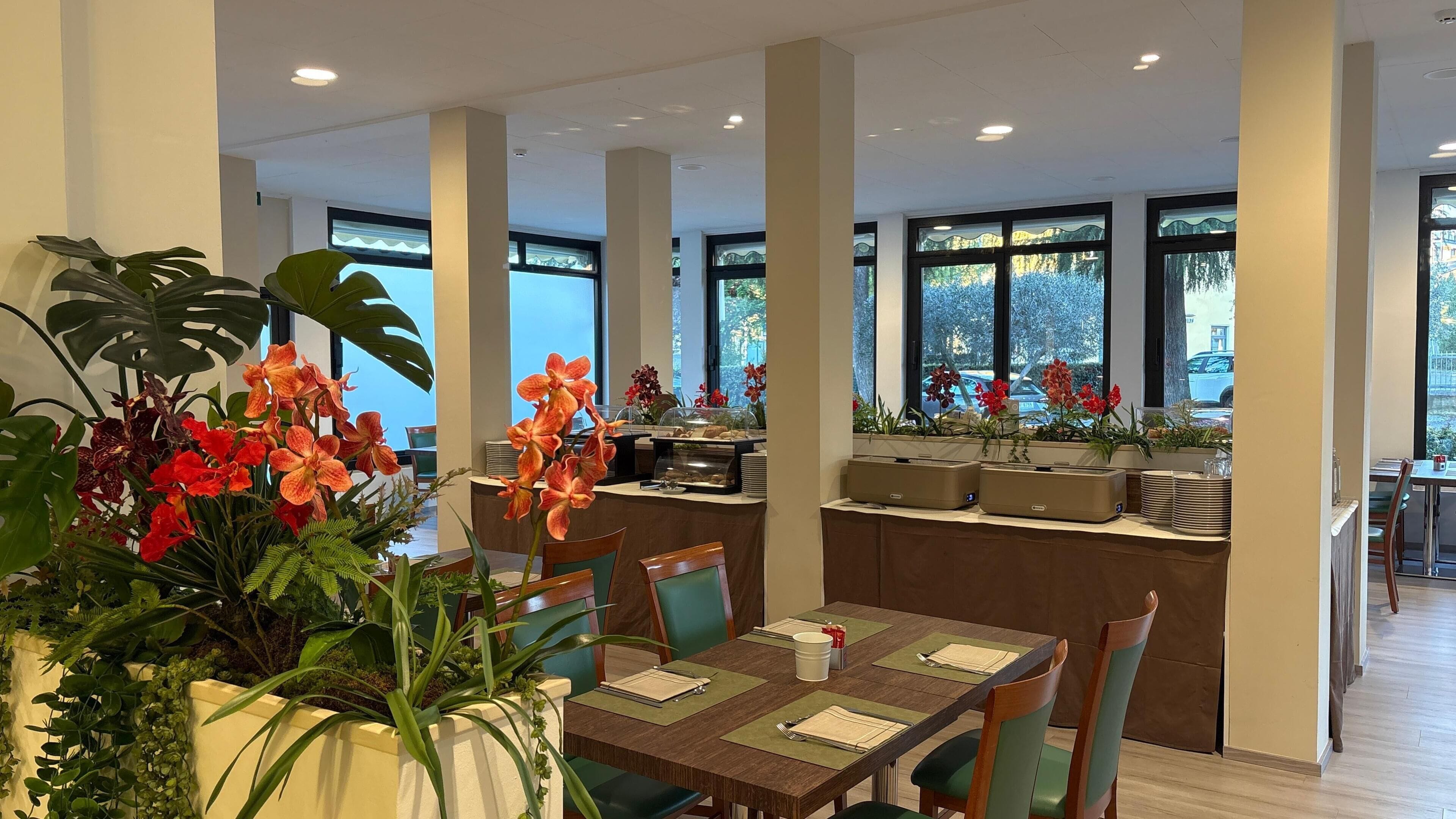 A modern dining area with high ceilings, large windows, and indoor plants.