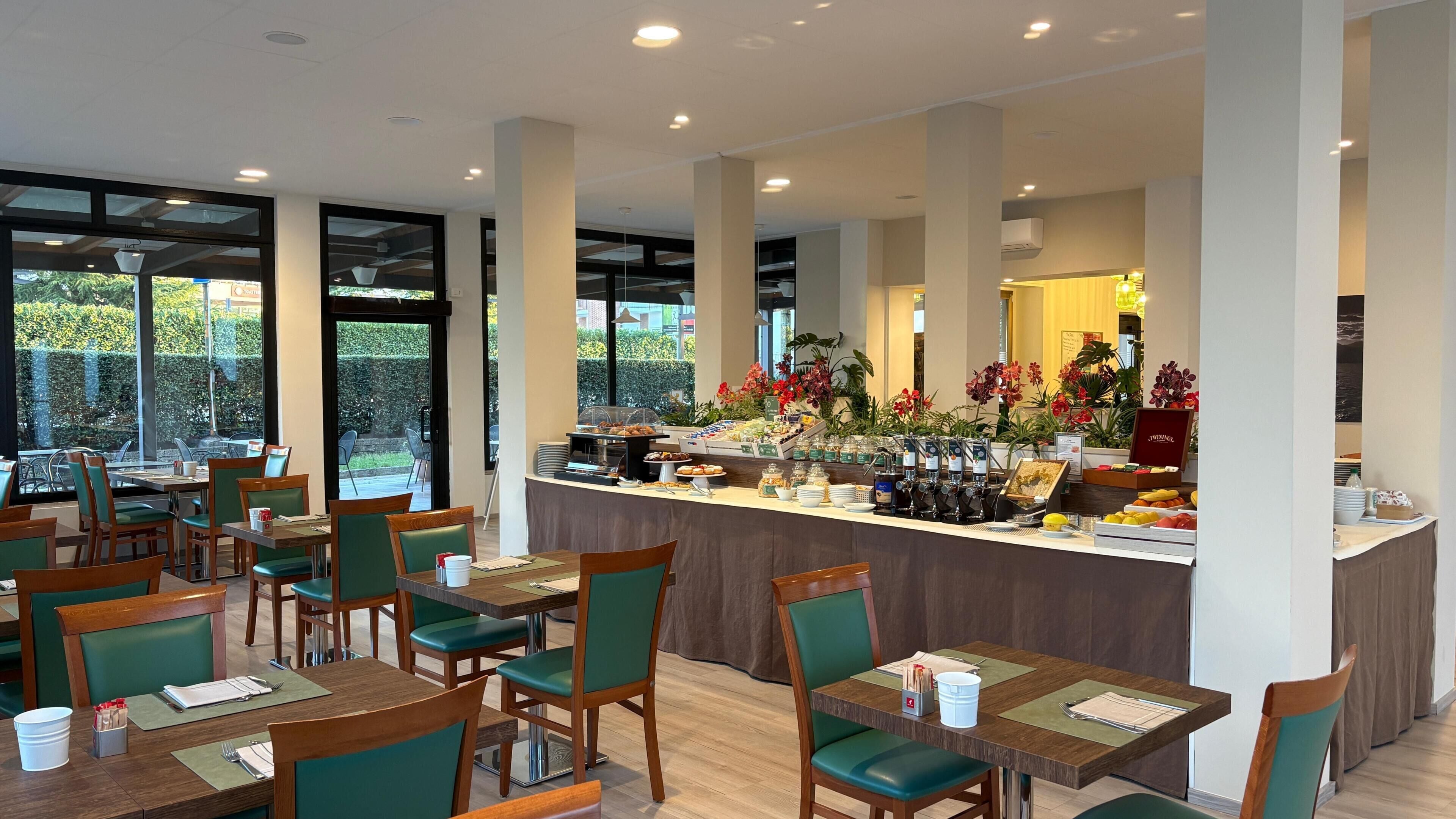 Un restaurante con un mostrador de buffet, sillas verdes y mesas.