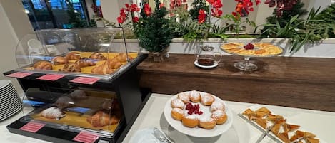 Un bufé de desayuno con pastelería, un plato de rosquillas y una taza de café.