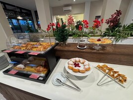 Un bufé de desayuno con pastelería, un plato de rosquillas y una taza de café.