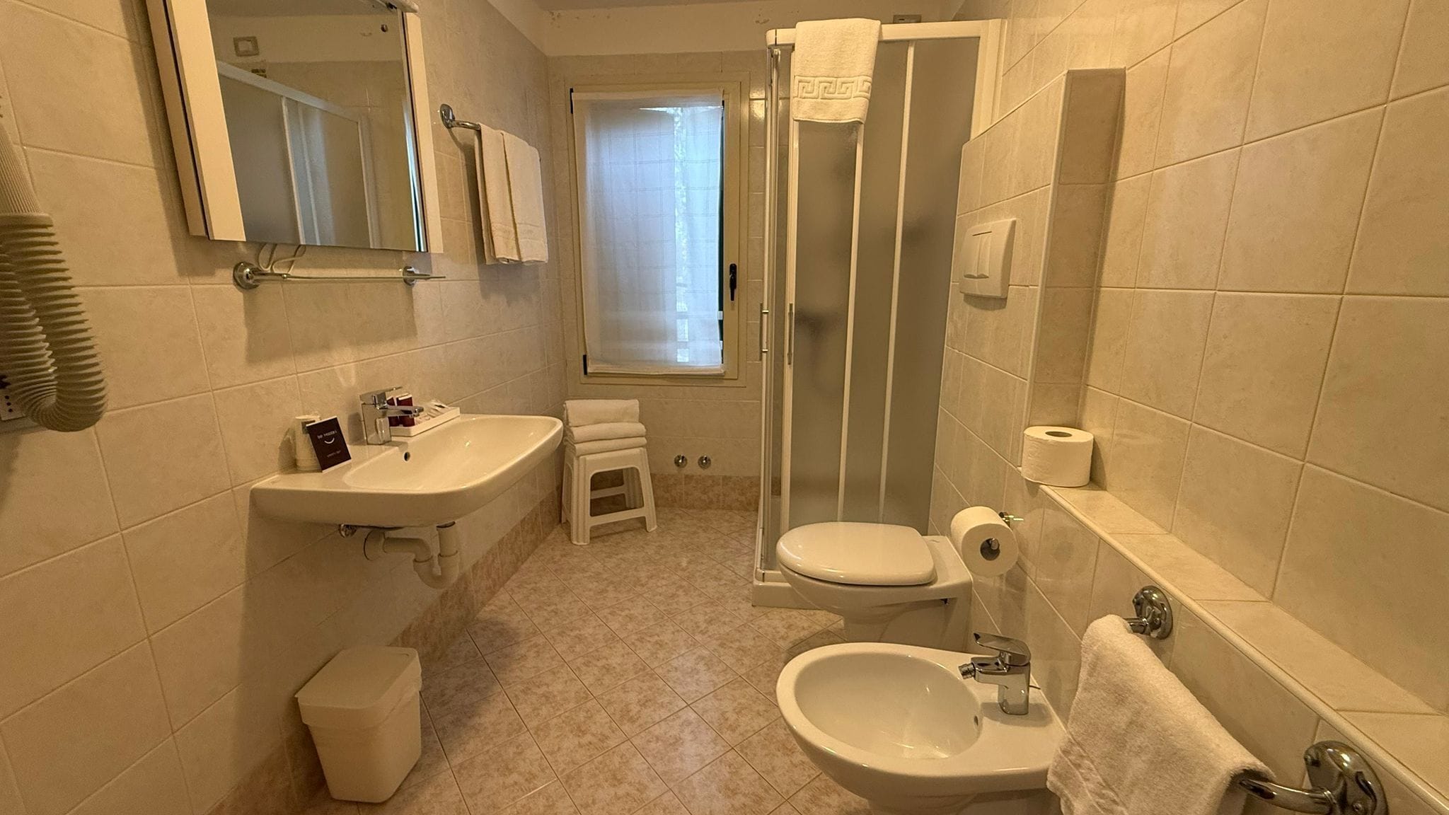 A modern bathroom with a sink, toilet, bidet, and shower.