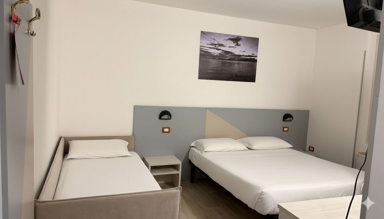 Habitación de hotel con dos camas individuales, una mesita pequeña y una mesita de noche. Hay un cuadro en la pared sobre las camas.