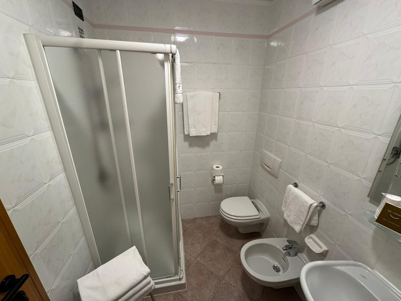 A bathroom with a glass-enclosed shower, a toilet, a bidet, and a sink.