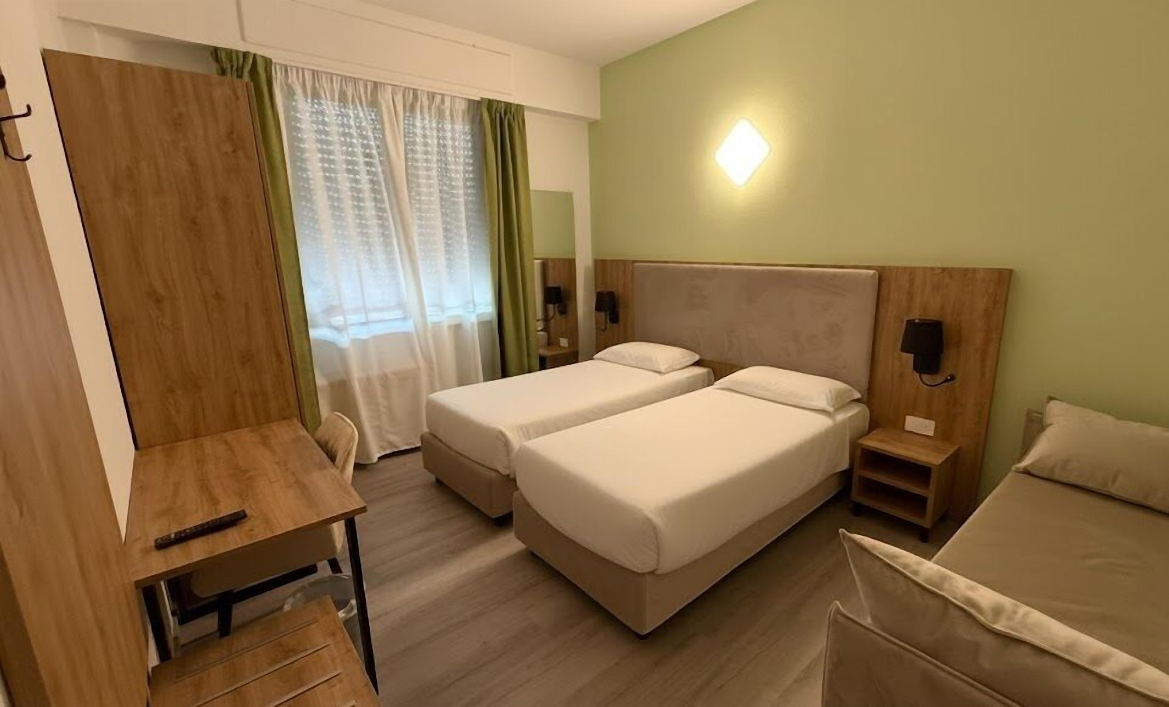 A hotel room with two beds, a desk, and a chair.