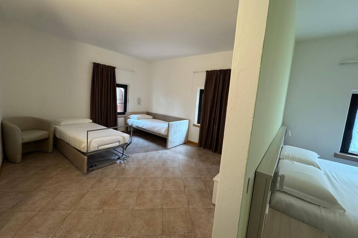 A hotel room with two single beds, a sofa, and a small table.