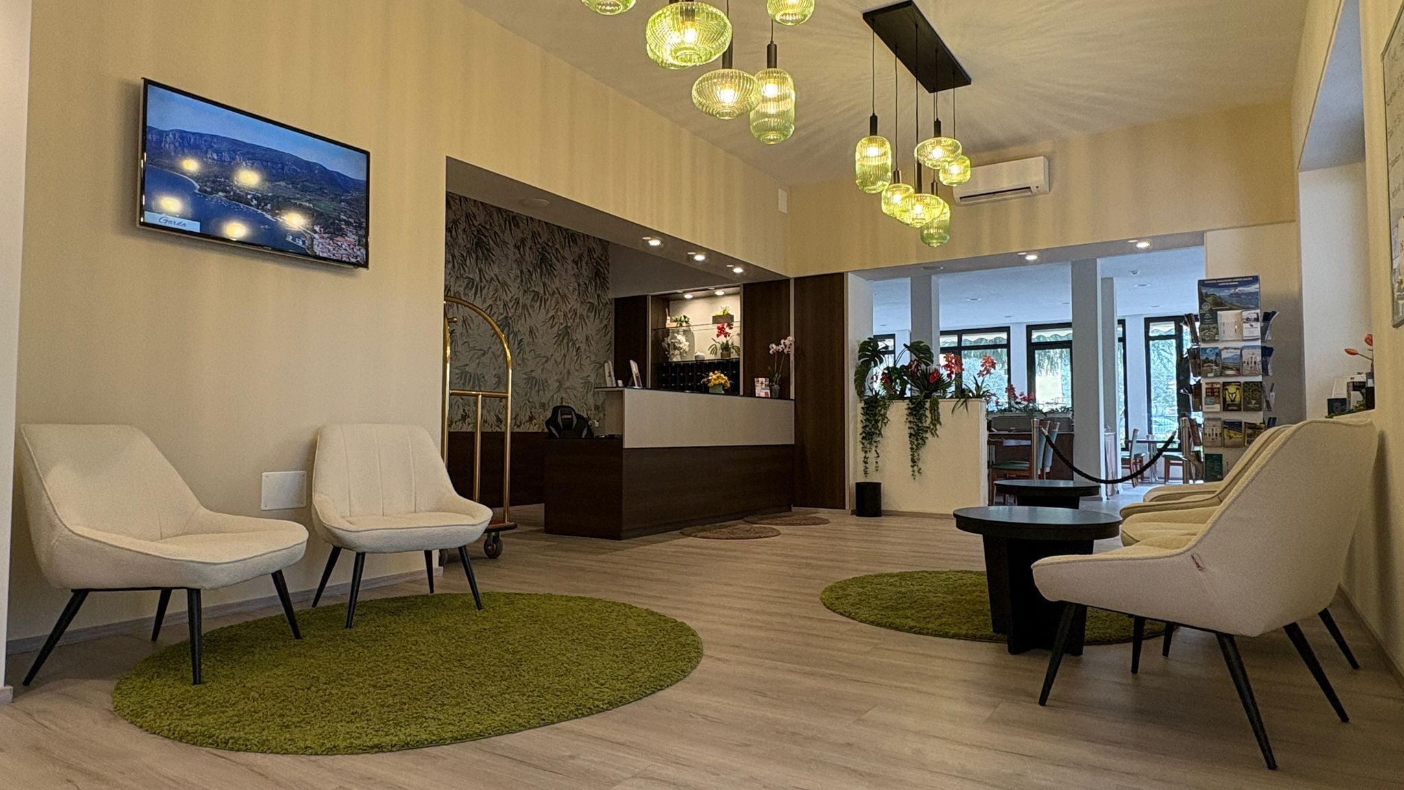 Un hall de hotel con mostrador de recepción, zona de estar y un ventanal grande.