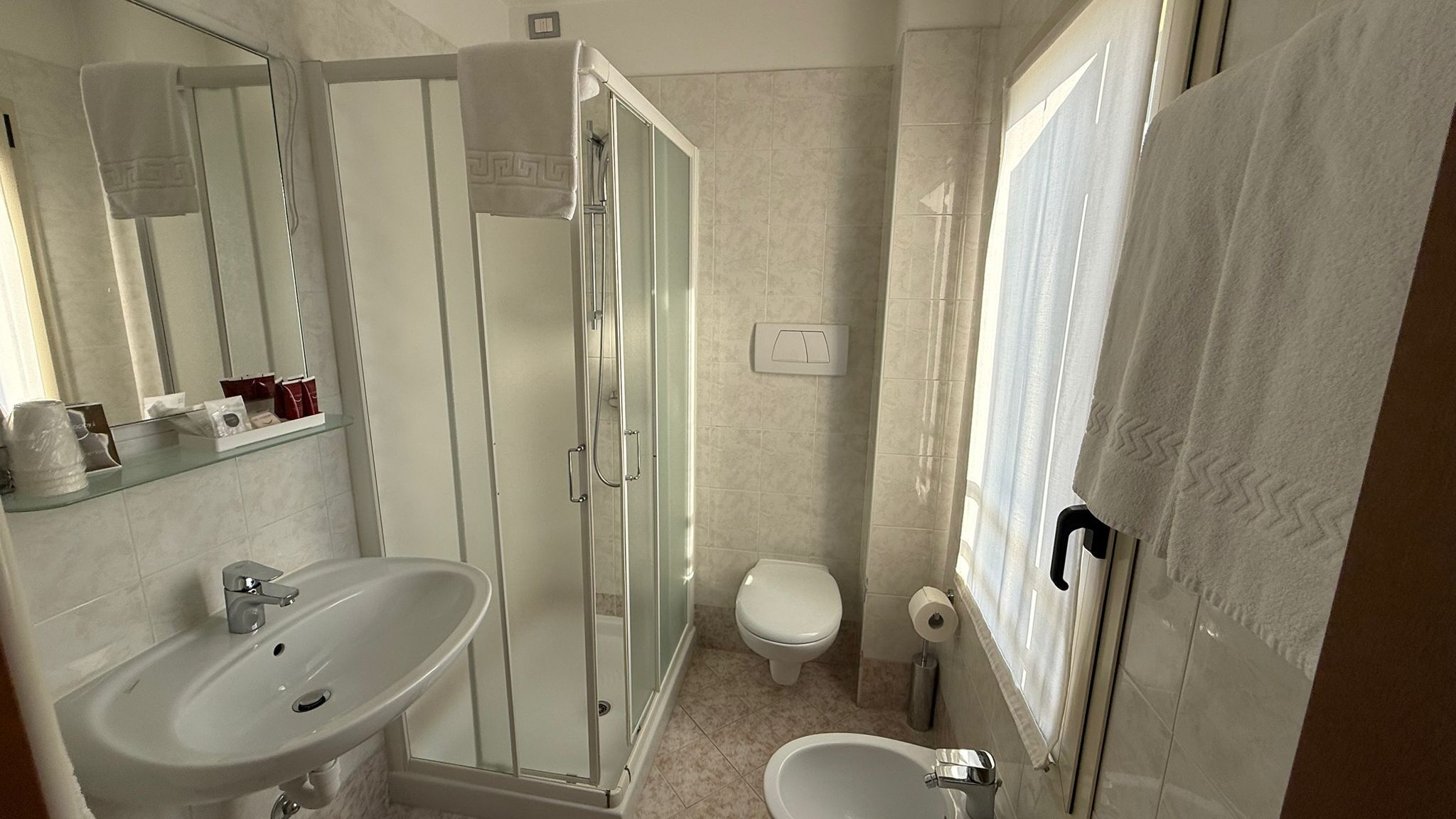 Une salle de bain avec une douche à parois de verre, un lavabo, des toilettes et un bidet.