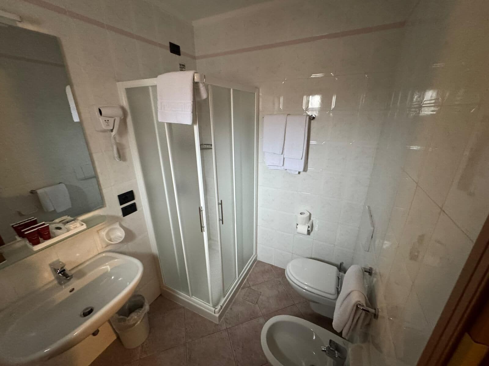 Une salle de bain équipée d’un lavabo, d’un bidet, de toilettes et d’une douche à parois en verre.