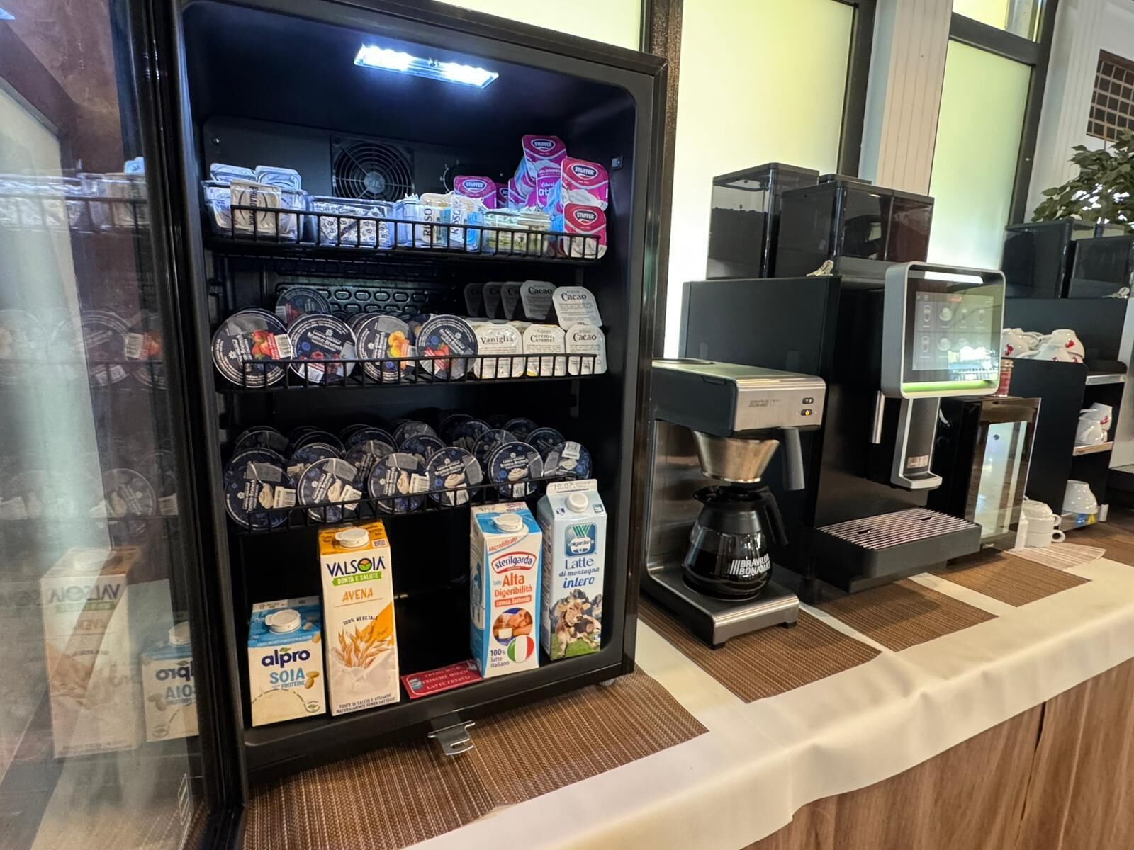 A coffee station with a coffee machine, a selection of coffee pods, and milk cartons.