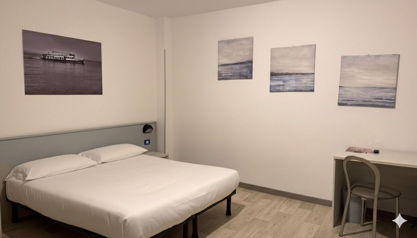 Ett sovrum med en säng, ett skrivbord och en stol. Det finns tre tavlor på väggen.