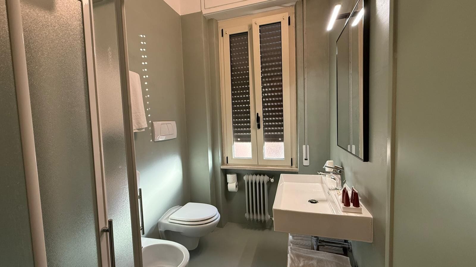 A compact bathroom with a toilet, a sink, and a window.